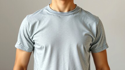 Close-up of a man's torso wearing a plain grey t-shirt with short sleeves and a crew neck against a neutral background