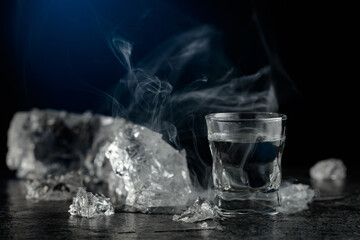 Crystal clear vodka in a glass on a black stone table.