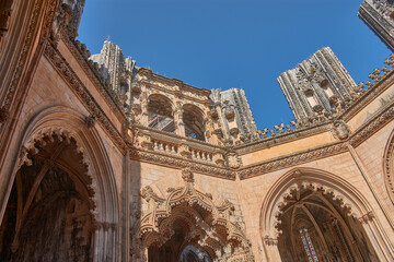 Architectural detail of the unfinished chapel in Batalha with Gothic tracery and pinnacles on a clear, monumental day