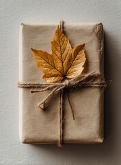 Gift box wrapped in kraft paper, tied with twine, featuring a dried autumn leaf