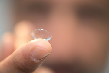 finger holds a contact lens