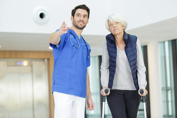 Obraz premium male doctor pointing to female senior patient in cruches