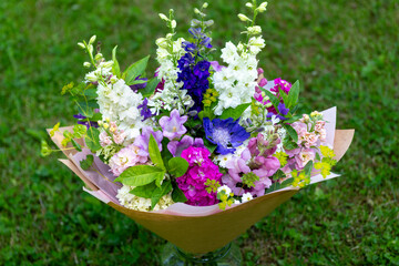 Wrapped flower bouquet made of mixed spring flowers. Beautiful pink, white and blue fresh flowers arrangement. Birthday bouquet with larkspur and matthiola stock.