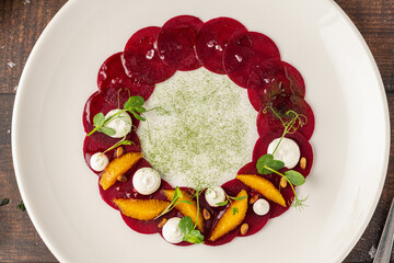 Beet carpaccio with orange slices, fresh greens and cream dots