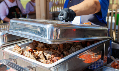 A man is cooking food in a large silver pan
