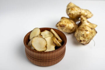 Jerusalem artichoke with slices pieces in the bowl isolated on a white background.