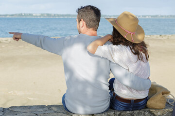 romantic mid adult couple pointing from beach