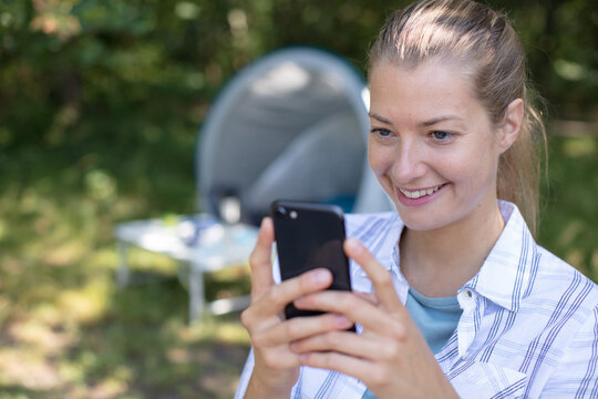 woman on camping holiday looking at her smartphone - Powered by Adobe