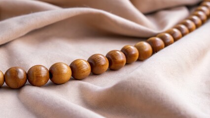 Smooth wooden beads are elegantly draped over soft fabric, creating a warm, inviting aesthetic.