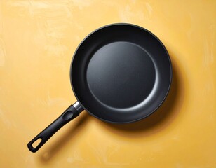 Simple black frying pan on a textured yellow background, ready for cooking.