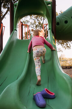 Young child climbing slide on park playground