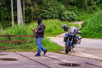 A man wearing black jacket and face cover with his motorbike
