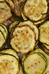 A close-up on stacked slices of fried zucchini with caramelized and browned edges, emphasizing the glossy texture and the slightly translucent flesh