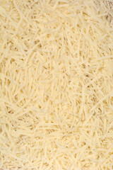 A detailed close-up shot shows a textured background completely filled with shredded yellow Parmesan cheese