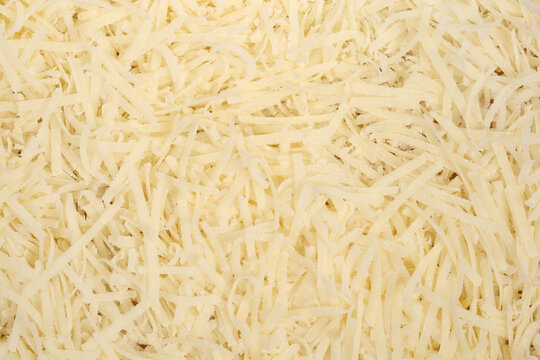 A detailed close-up shot shows a textured background completely filled with shredded yellow Parmesan cheese