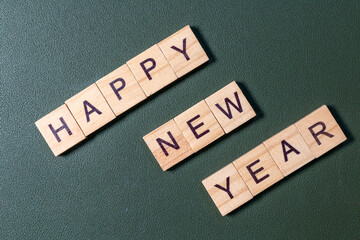 Wooden letter tiles spelling Happy New Year arranged neatly on a textured green background