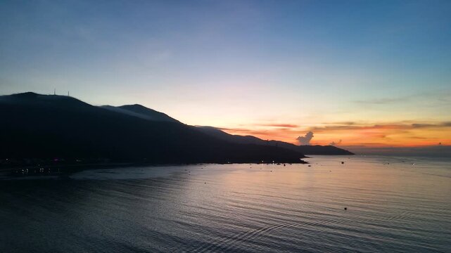 Warm sunlight illuminating son tra mountain's coastal landscape, golden rays casting ethereal glow across serene da nang bay during spectacular dawn moment