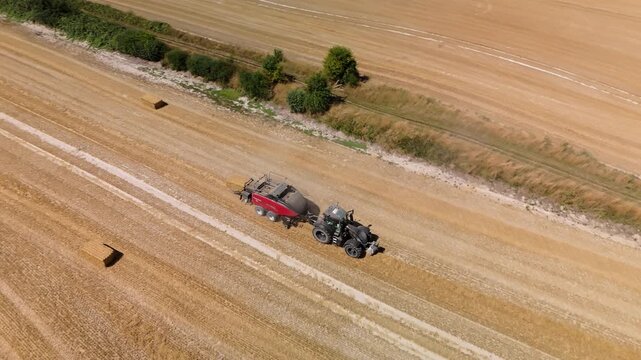 Aerial shot of Hay Baler working in a field during the summer in Wiltshire, UK