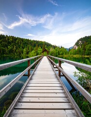 Wooden bridge extending over a tranquil lake towards a small structure