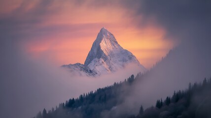 Majestic mountain peak surrounded by mist and colorful sunrise sky
