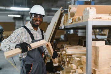 African american Carpenter holding wooden components in furniture factory