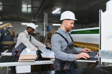 Furniture factory workers operating cnc machine for sofa production