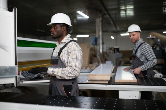 Furniture factory workers operating cnc machine for sofa production