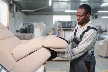 African american Furniture maker assembling sofa in upholstery workshop