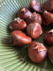 Close up of roasted chestnuts served on a green ceramic plate
