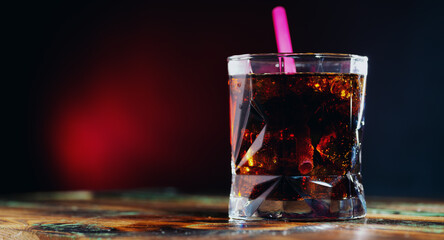 Whiskey and cola in a glass glass with ice on the table