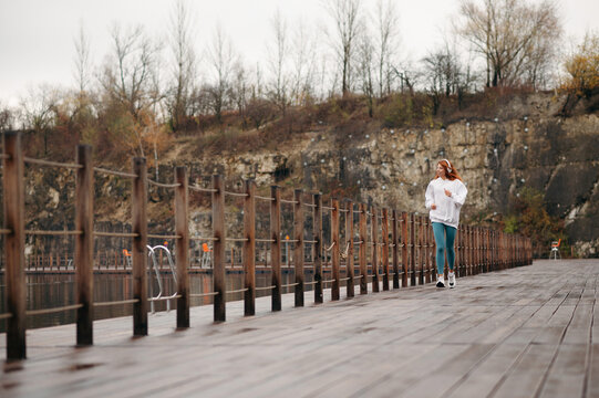 Girl in white hoodie with headphones on her head running