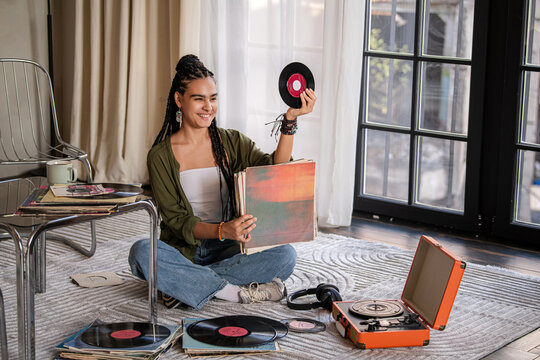 girl sits among vinyl records, showing one of them.