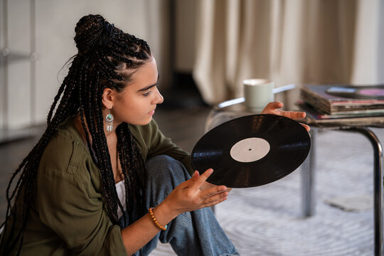 girl examines a vinyl record. Enjoying vintage sound.