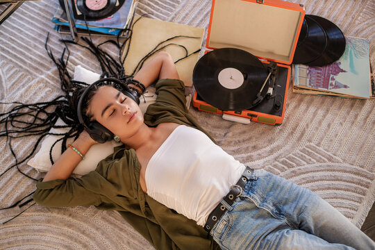 teenager with African braids listens to vinyl records on headphones