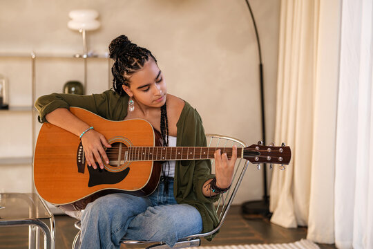 teenage girl plays an acoustic guitar at home.