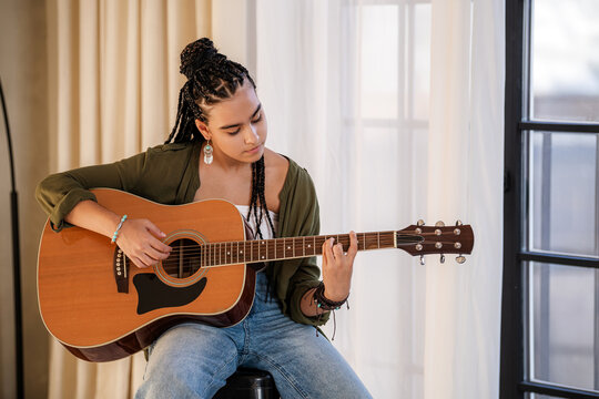 teenage girl playing acoustic guitar in a stylish living room.