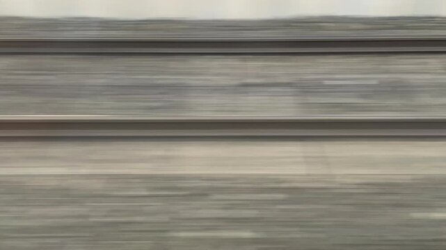 High-speed view of railway tracks in motion blur, captured from a moving train. Dynamic transportation background with lines in motion and earthy tones.
