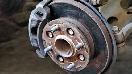 Closeup of a rusty car brake rotor showing wear and tear in a garage, highlighting the need for...