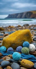 Colorful yarn balls on a pebbled beach, large yellow rock