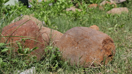 Old stone mortars resting in grassy field at archaeological site on sunny day, creating a sense of history and mystery.