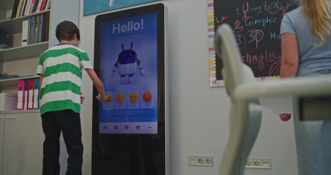 Boy Cheerfully Interacts With AI Mood Tracker. Students Show Positive Emotions in Class. Educational Technologies, Developing Emotional Intelligence, and Caring For Children's Mental Health. Handheld.