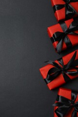 Vertical view of red gift boxes with bows on black background. Space for text