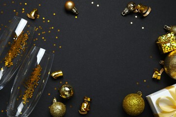 Top view of festive Christmas background with champagne glasses and decorations on black background. Space for text