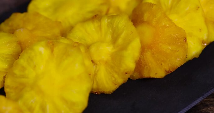 dried ripe yellow pineapple fruits on a black slate board, cut into rings and dried yellow clean slices of ripe pineapple for long-term storage and used as a sweet