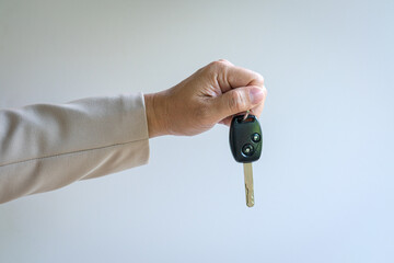 Man holding a car key. Against light background.