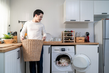 Asian mature man doing laundry in kitchen at home.