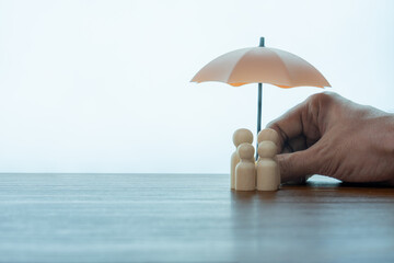 Umbrella and wooden dolls with copy space. Family protection and insurance coverage concept.