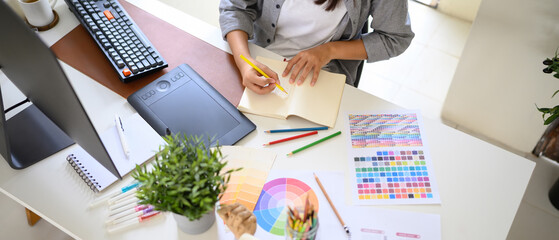 Creative graphic designer sketching logo ideas with colored pencils in a notebook