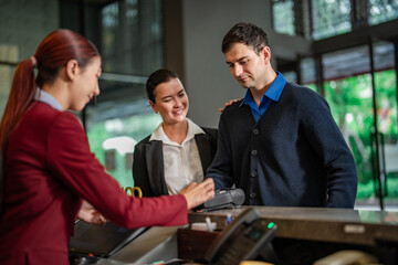 Hotel staff in formal uniform guiding travelers during check-in procedure. Suitable for travel, tourism, and hospitality use.
