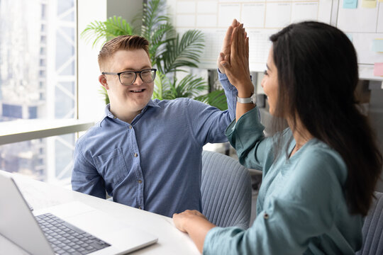 Two happy inclusive company coworkers making high five at workplace - Powered by Adobe
